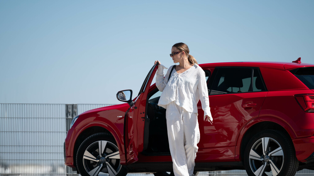 Frau mit Sonnenbrille vor einem roten Audi Q2